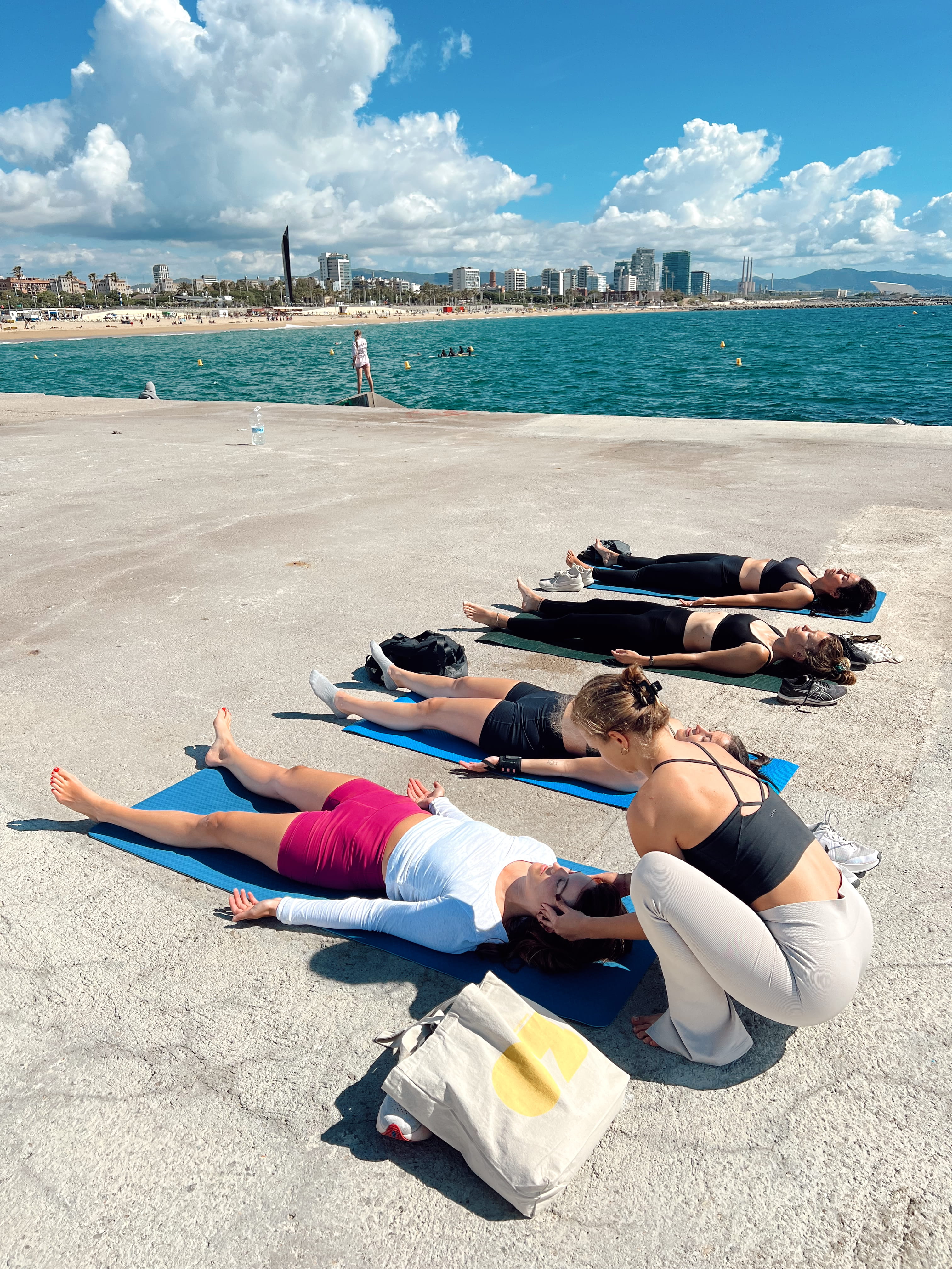 Group savasana on the Poblenou pier with the Barcelona skyline